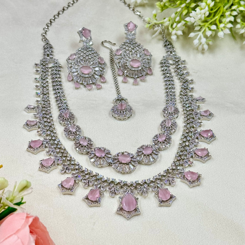 Necklace and earrings set with pink stones on a light background