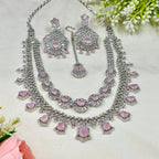 Necklace and earrings set with pink stones on a light background