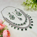 Jewelry set with necklace, earrings, and ring on a light background with flowers.