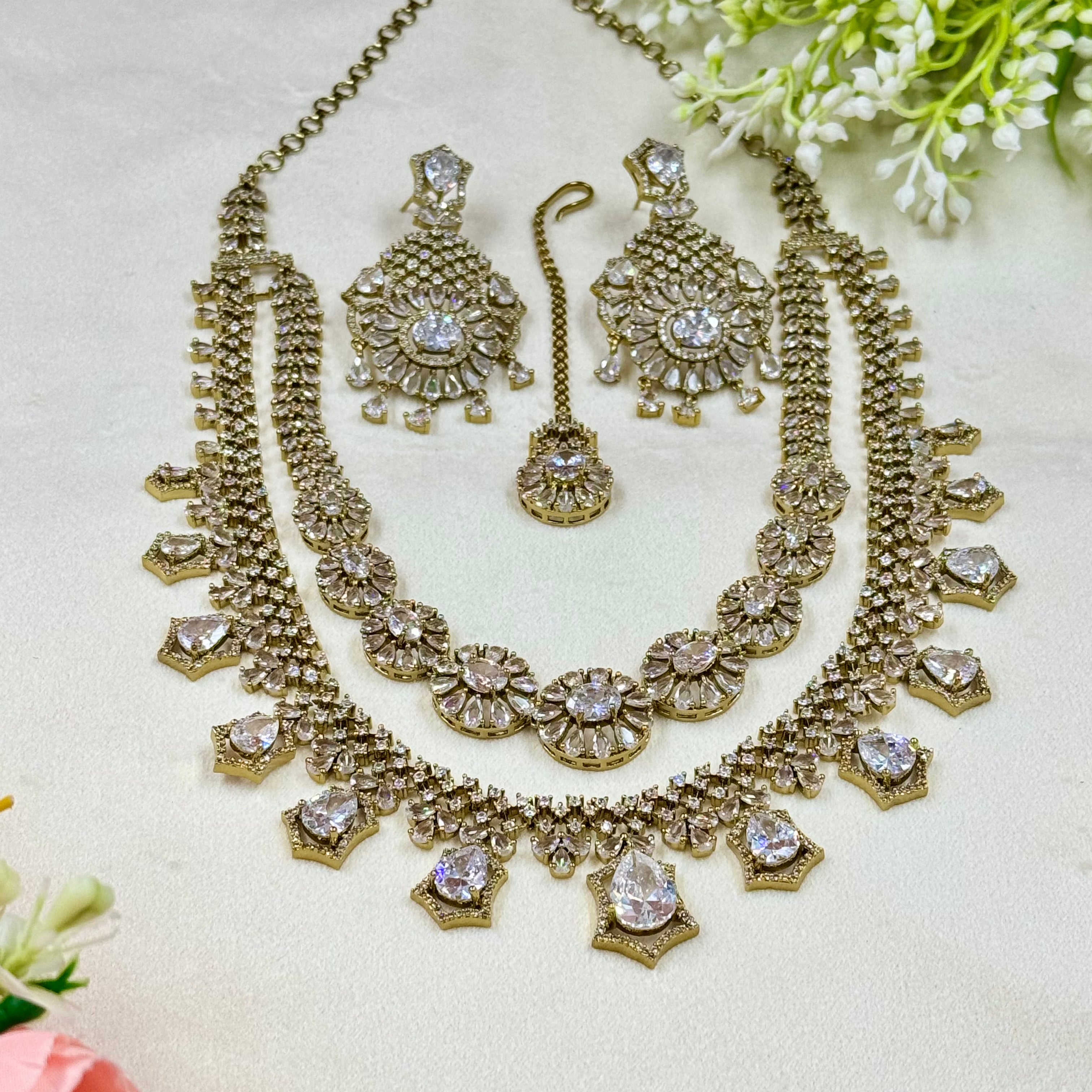 Gold necklace and earrings set with floral background