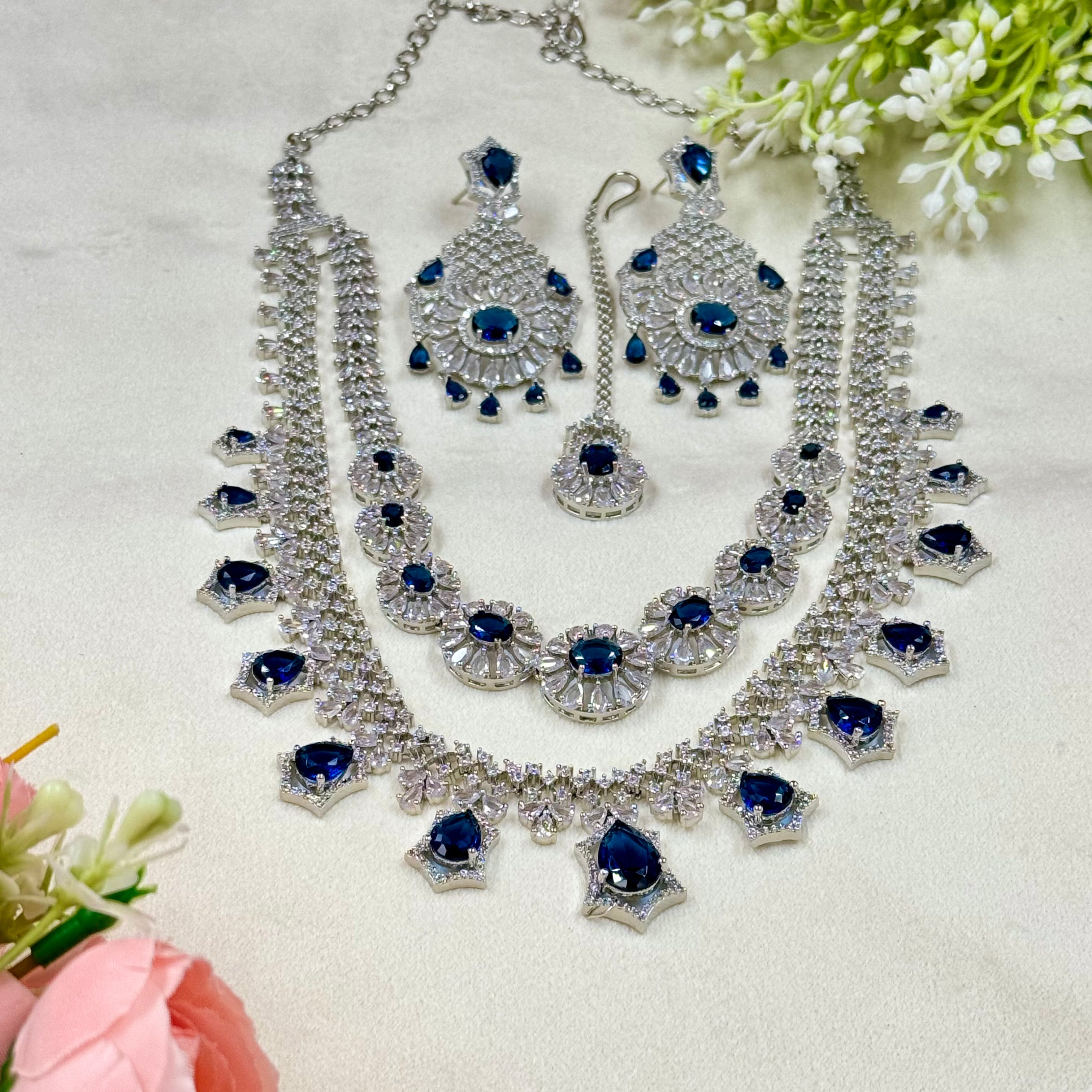 Jewelry set with necklace, earrings, and blue gemstones on a white background
