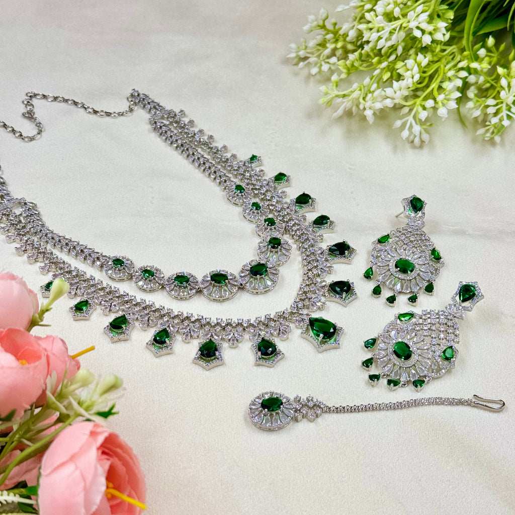Silver and green gemstone jewelry set with flowers on a light background