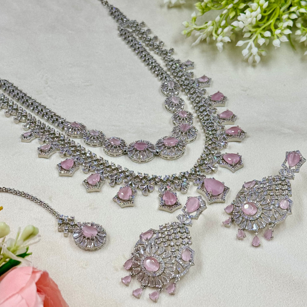 Silver and pink jewelry set on a light background with flowers.