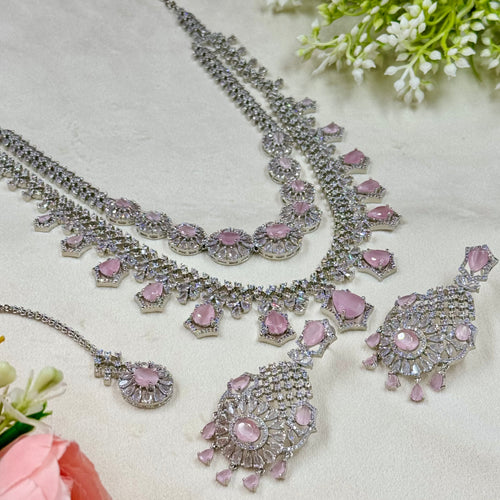 Silver and pink jewelry set on a light background with flowers.