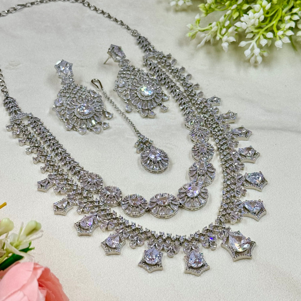 Silver jewelry set with necklace and earrings on a light background