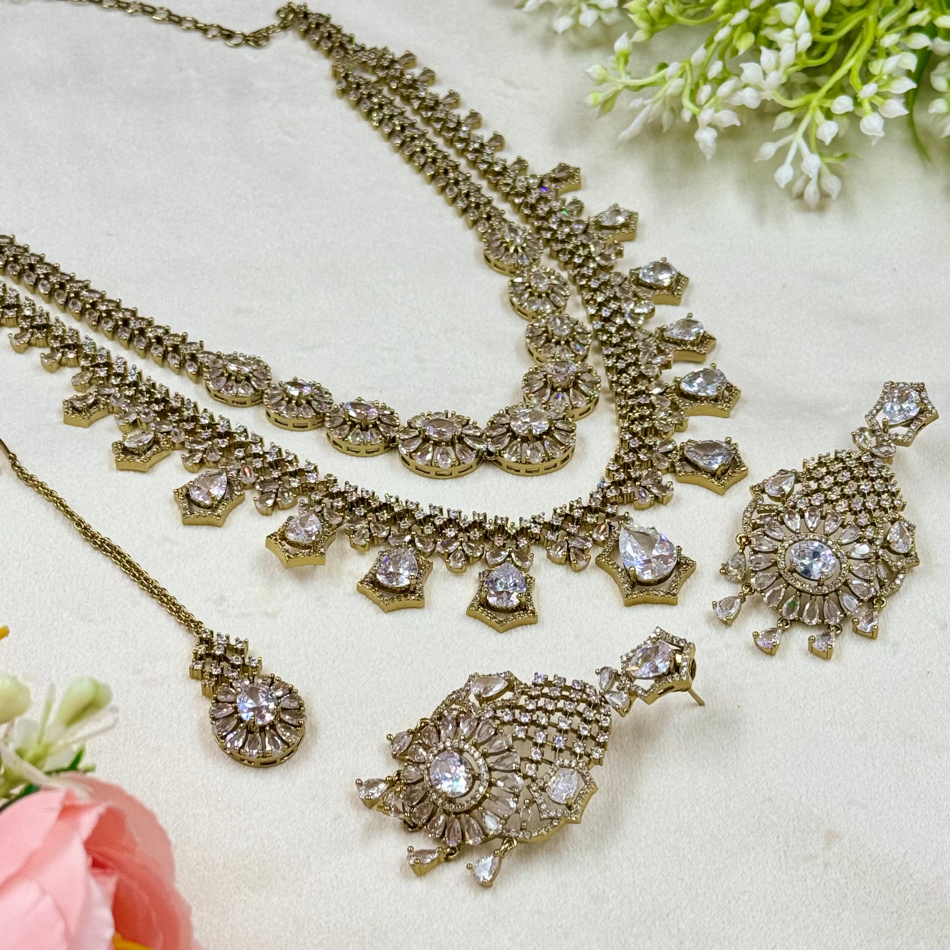 Gold jewelry set with necklace and earrings on a light background