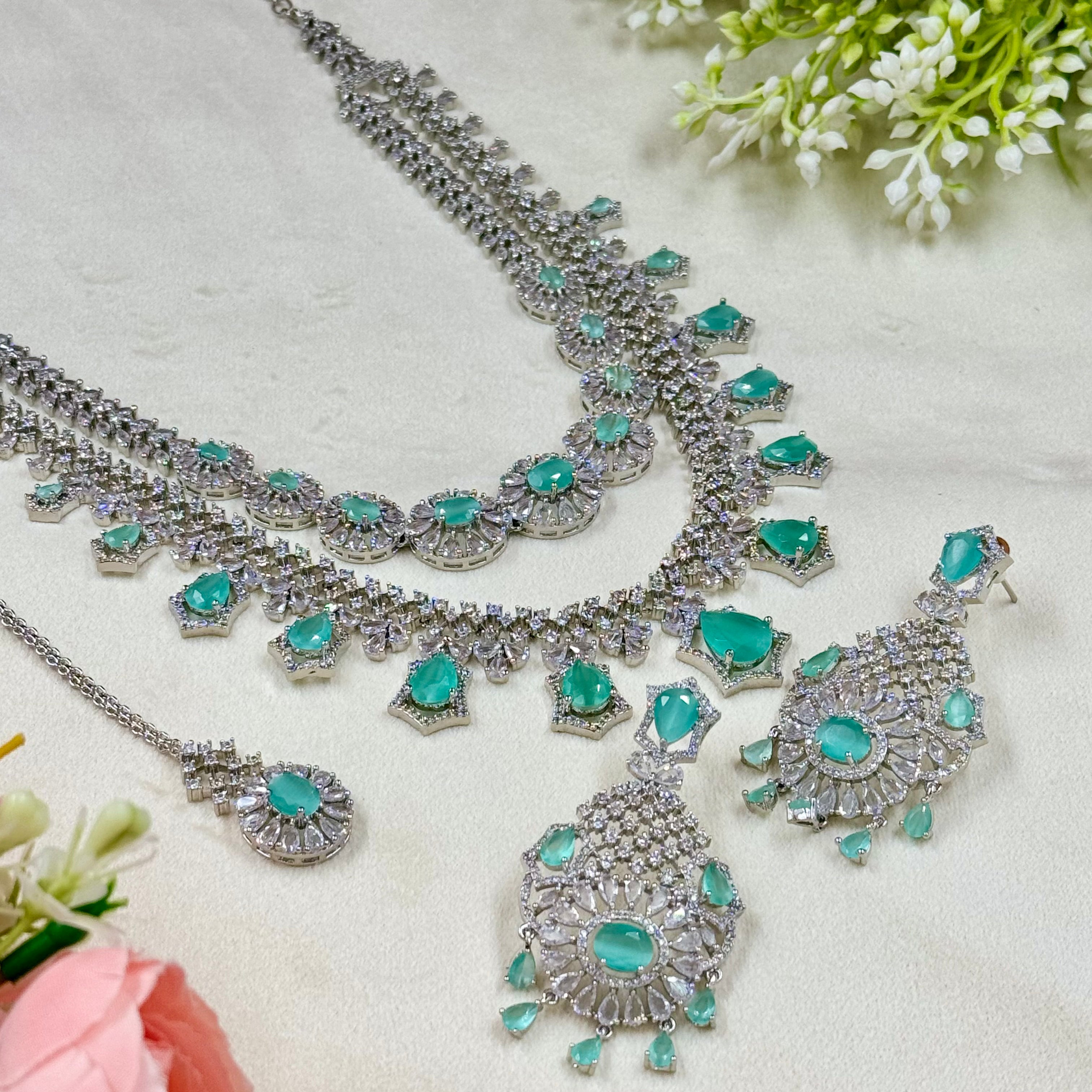 Silver and turquoise jewelry set on a light background with flowers.
