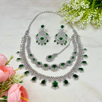 Jewelry set with necklace and earrings on a light background with flowers.