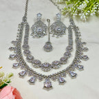 Silver necklace and earrings set with floral decorations on a light background