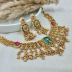 Gold necklace and earrings with gemstones on a white surface