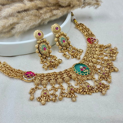 Gold necklace and earrings with gemstones on a white surface