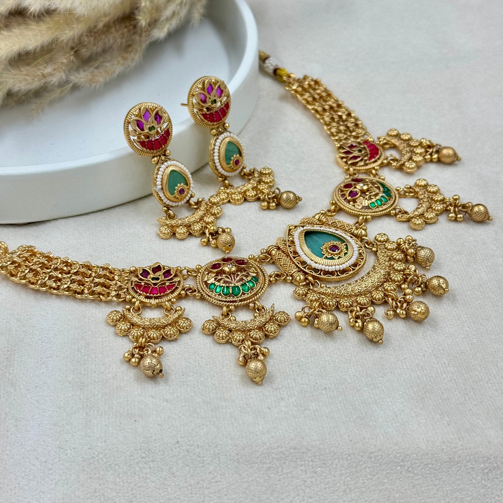 Ornate gold necklace with gemstones on a light background