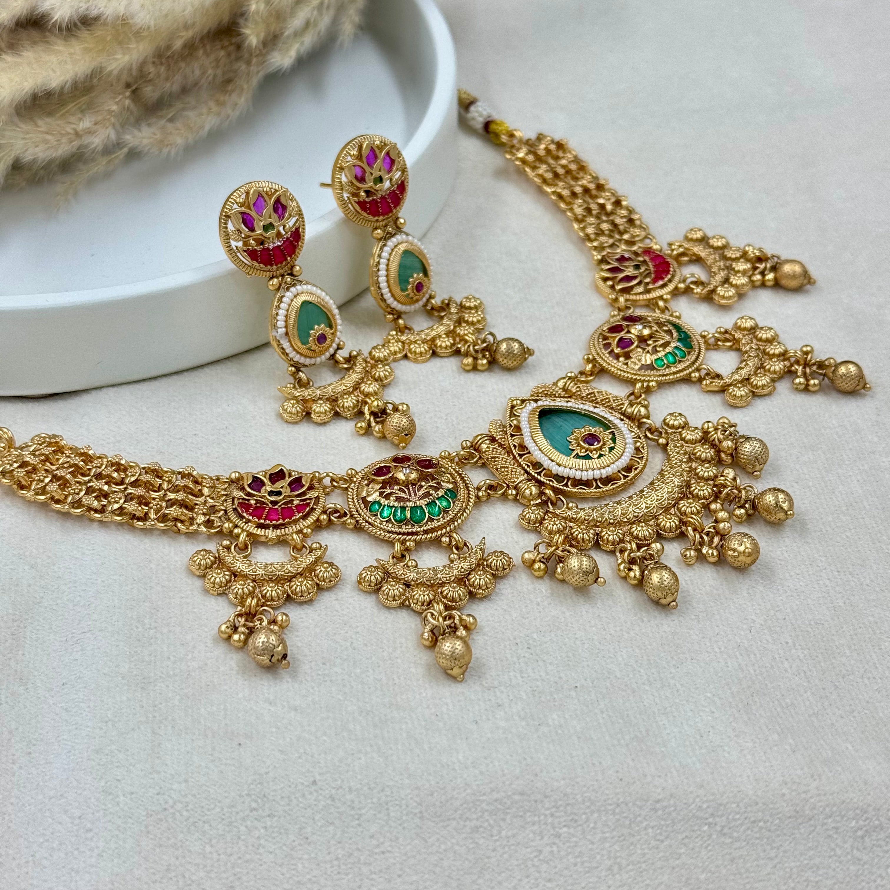 Ornate gold necklace with gemstones on a light background