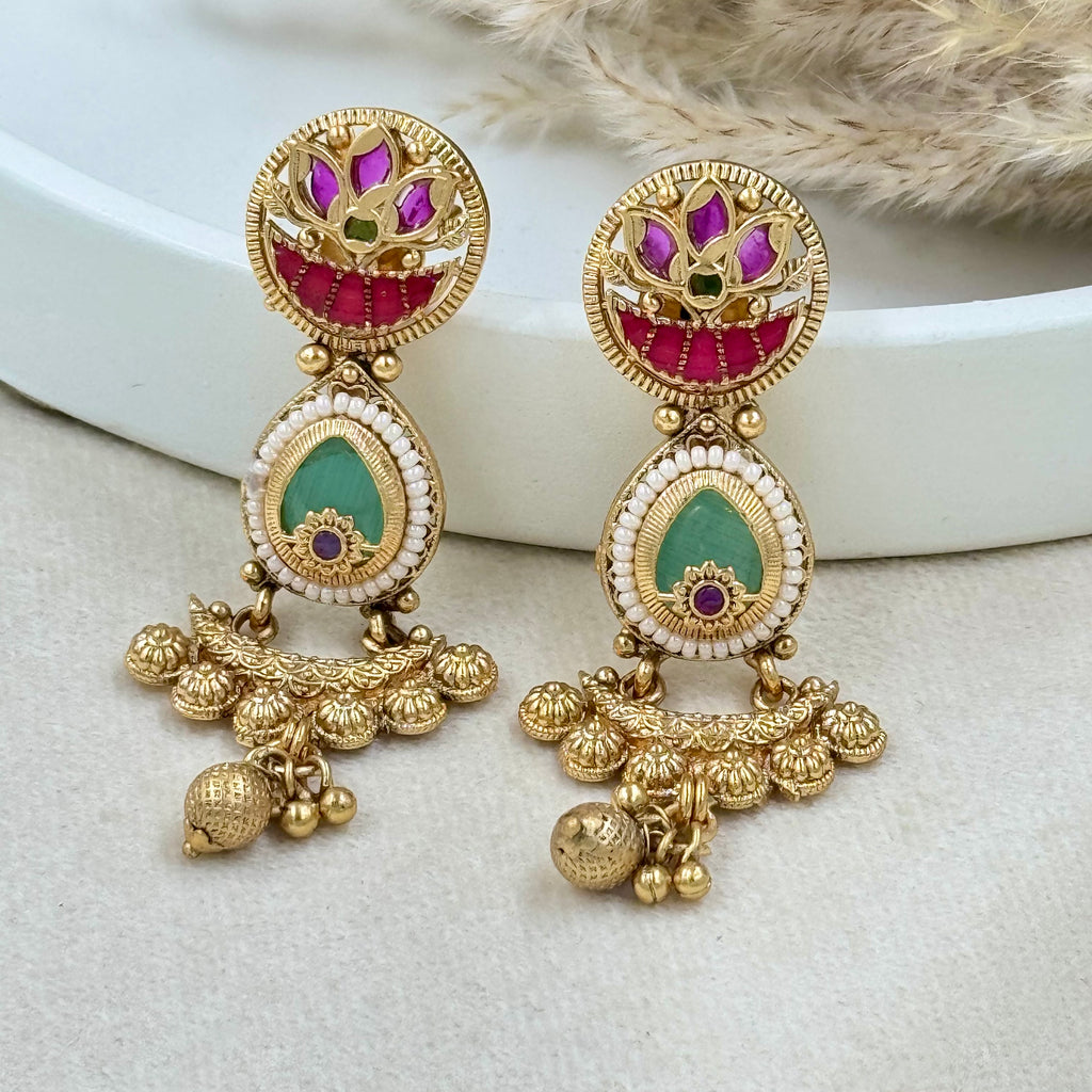 Gold earrings with colorful gemstones on a white surface