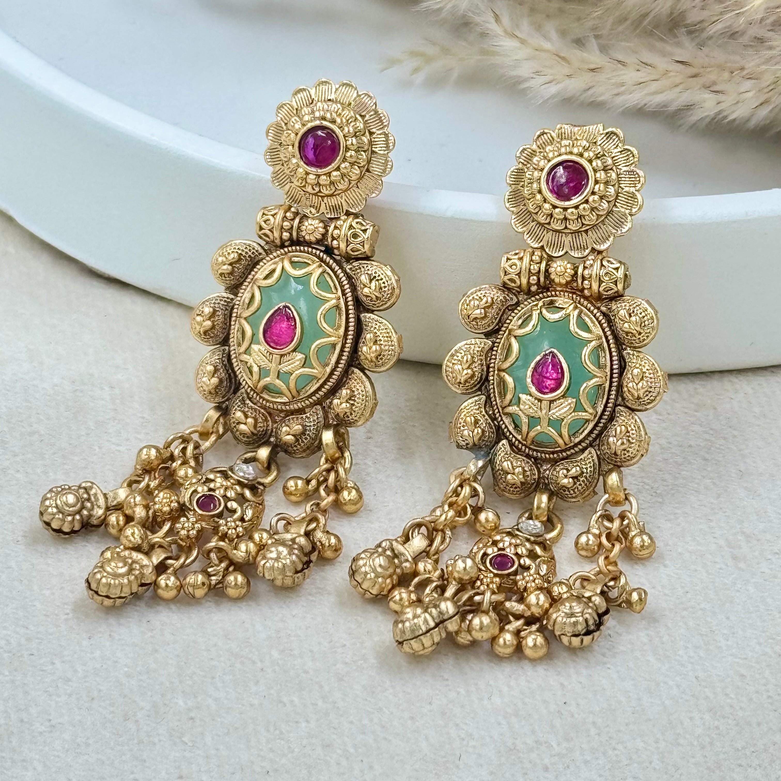 Ornate gold earrings with gemstones on a light background
