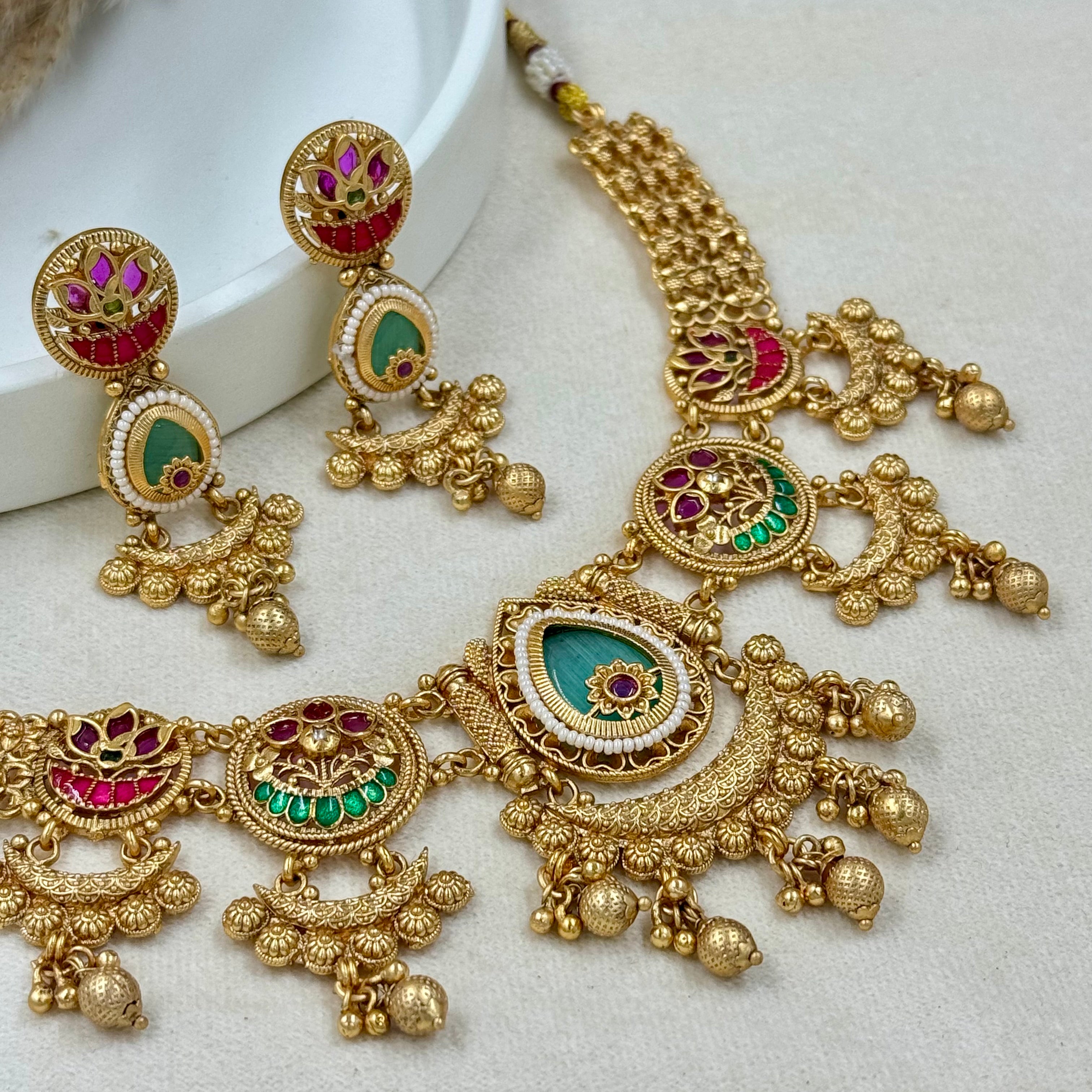 Gold jewelry set with necklace and earrings on a white surface