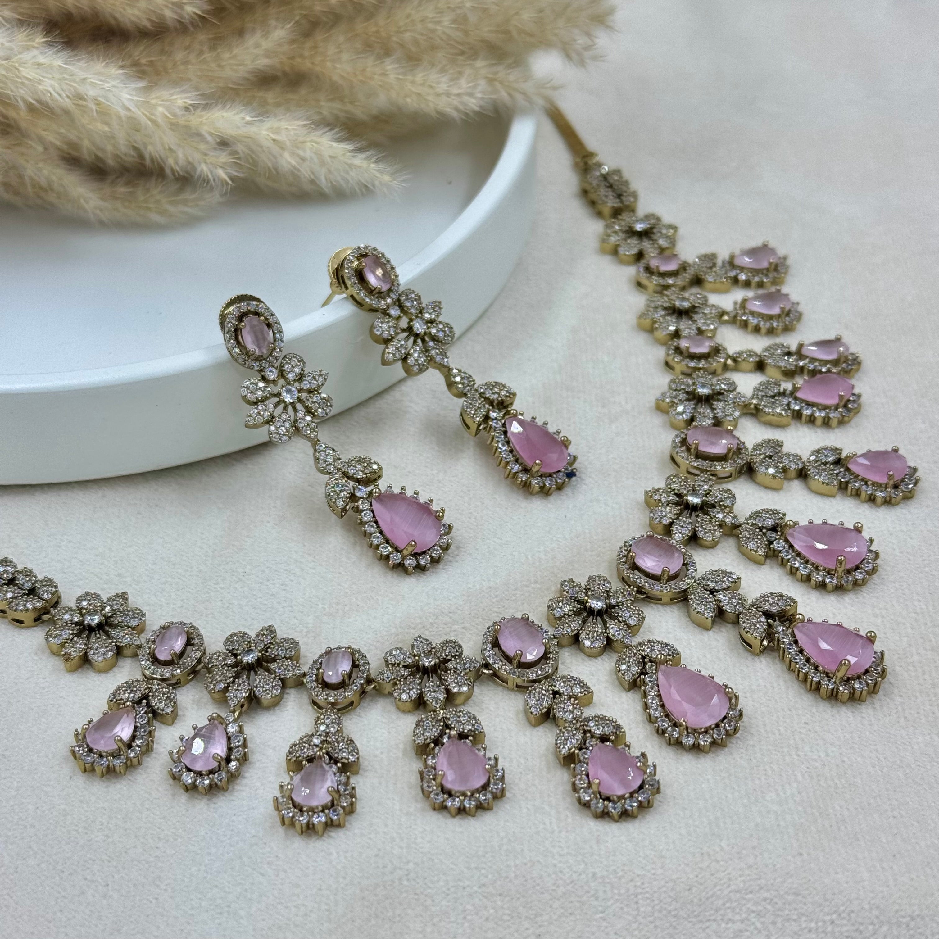 Jewelry set with pink stones on a neutral background