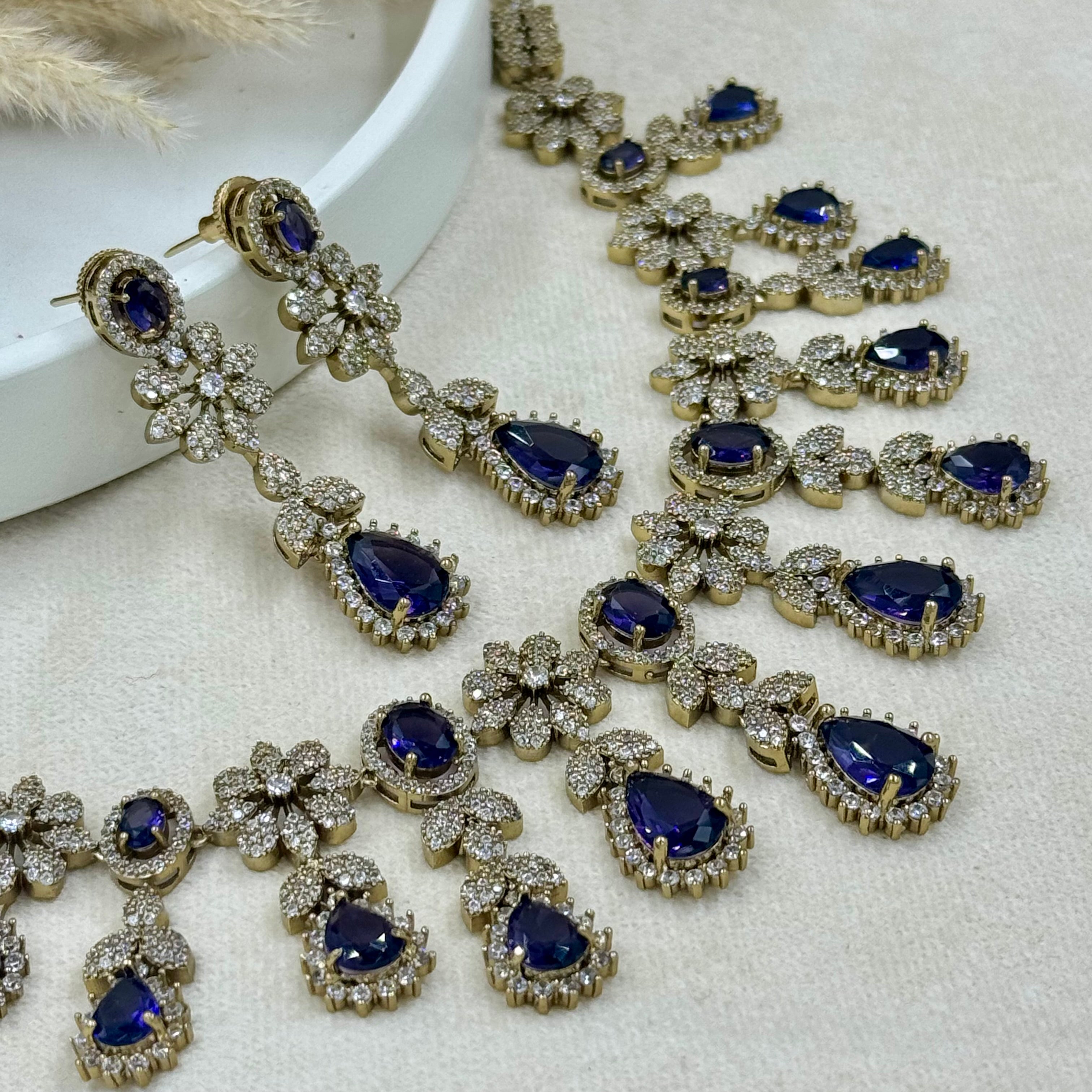 Jewelry set with blue gemstones and gold accents on a white surface