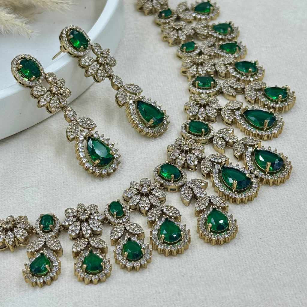 Jewelry set with green gemstones and gold accents on a light background