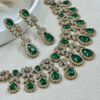 Jewelry set with green gemstones and gold accents on a light background