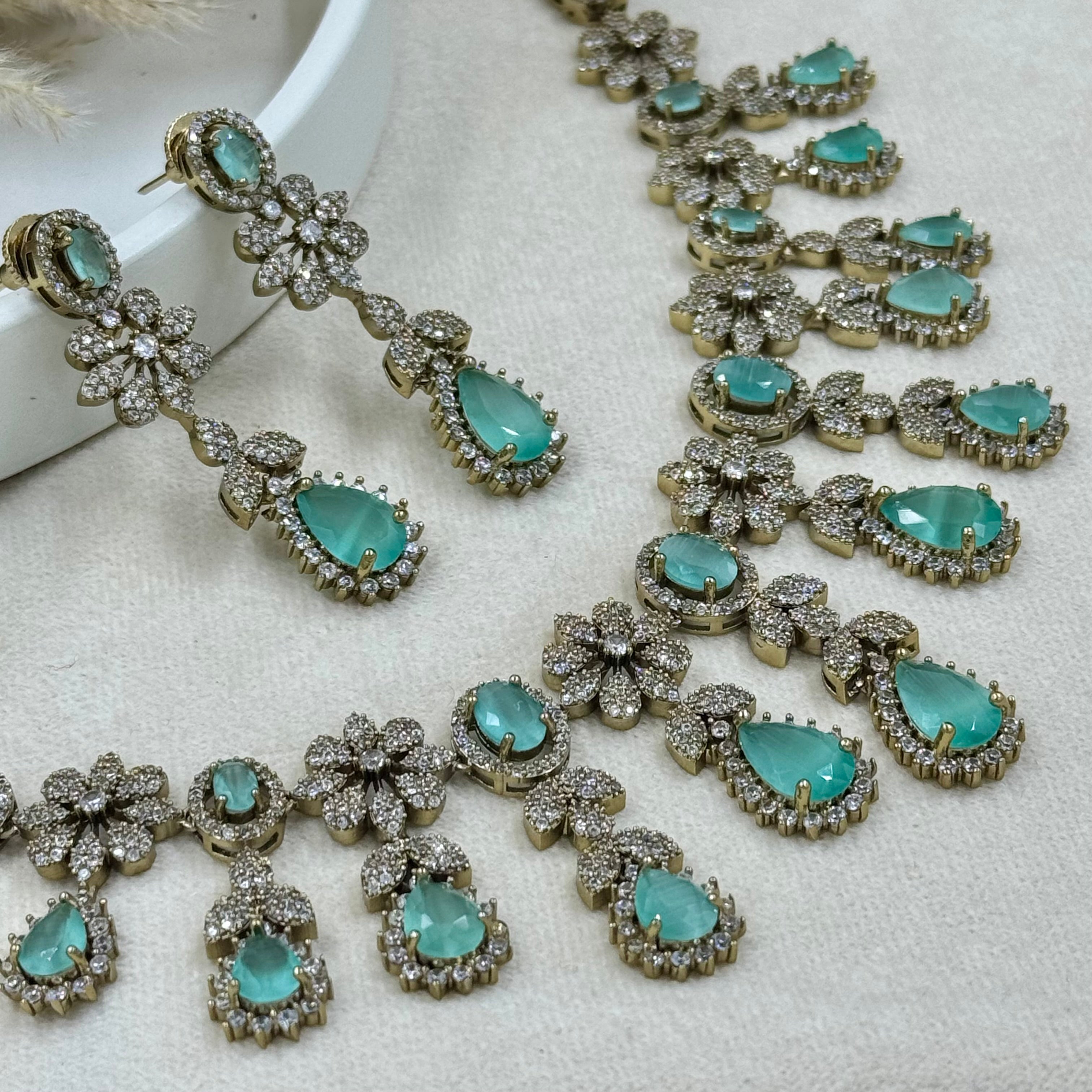 Turquoise gemstone necklace and earrings on a white fabric background