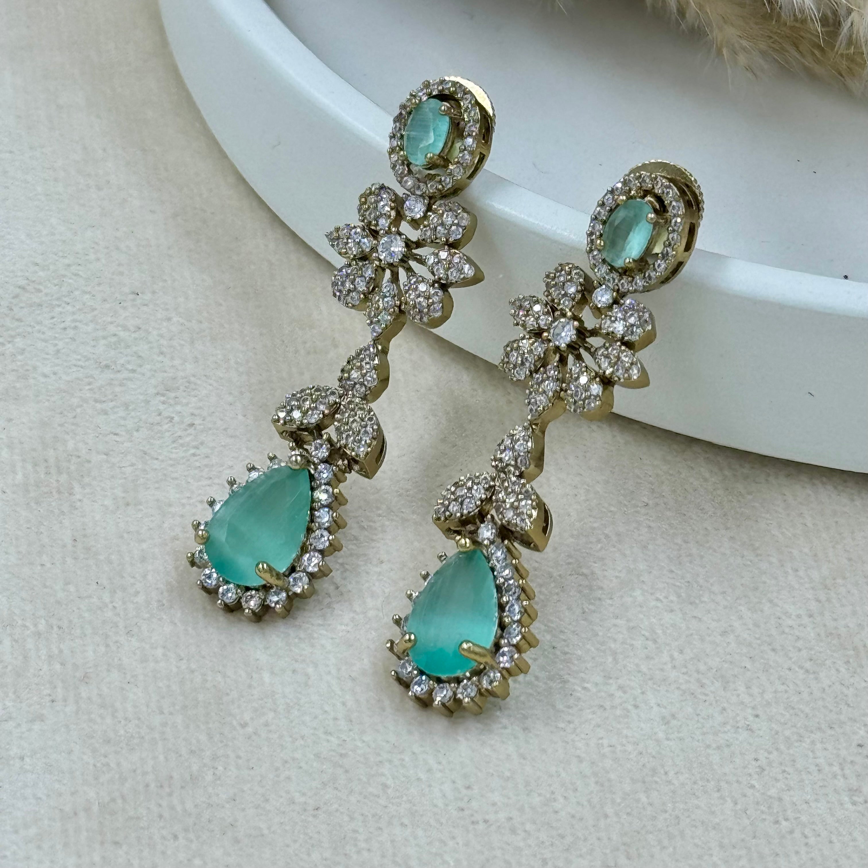 Pair of earrings with turquoise stones and gold accents on a light background