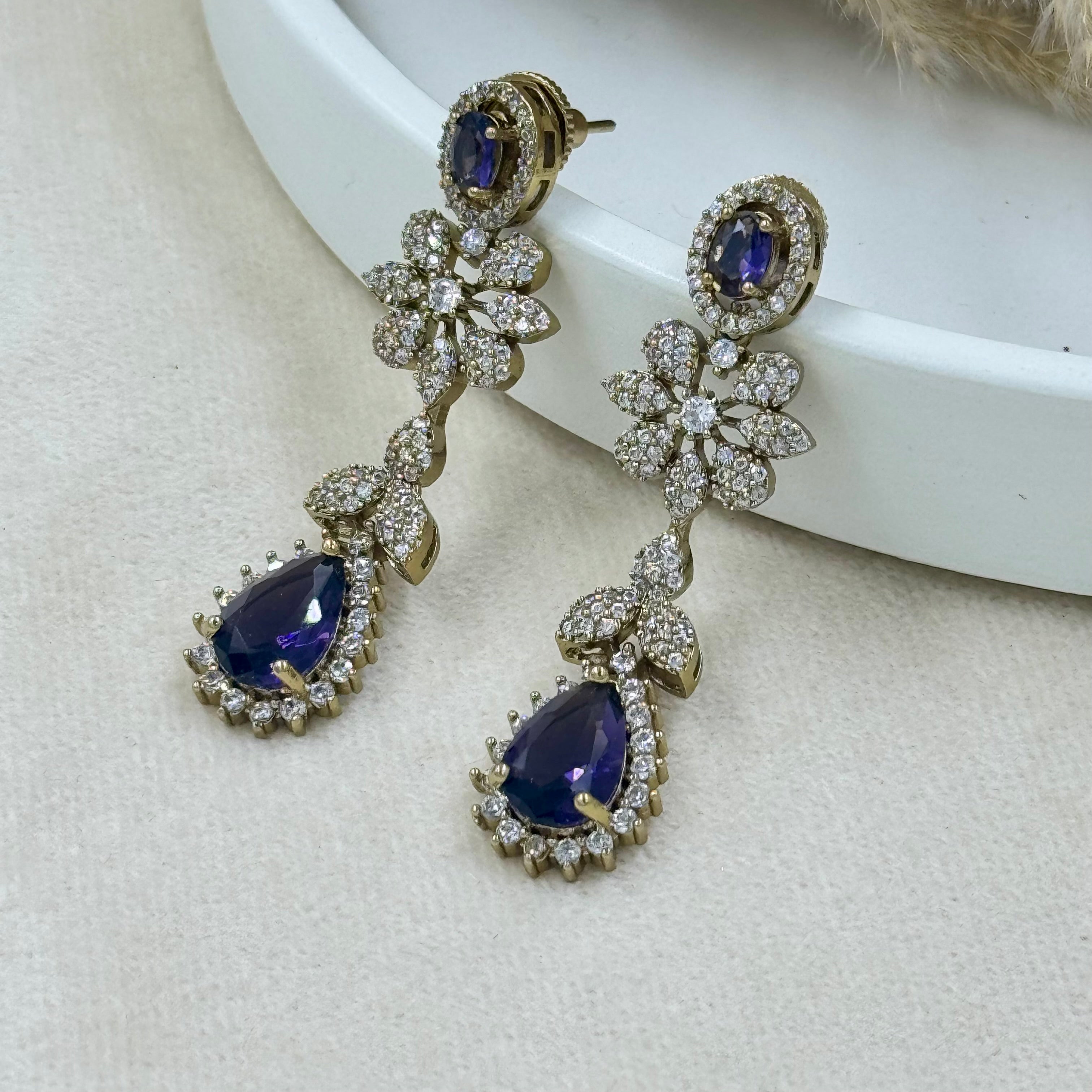 Pair of earrings with blue gemstones and gold accents on a white surface