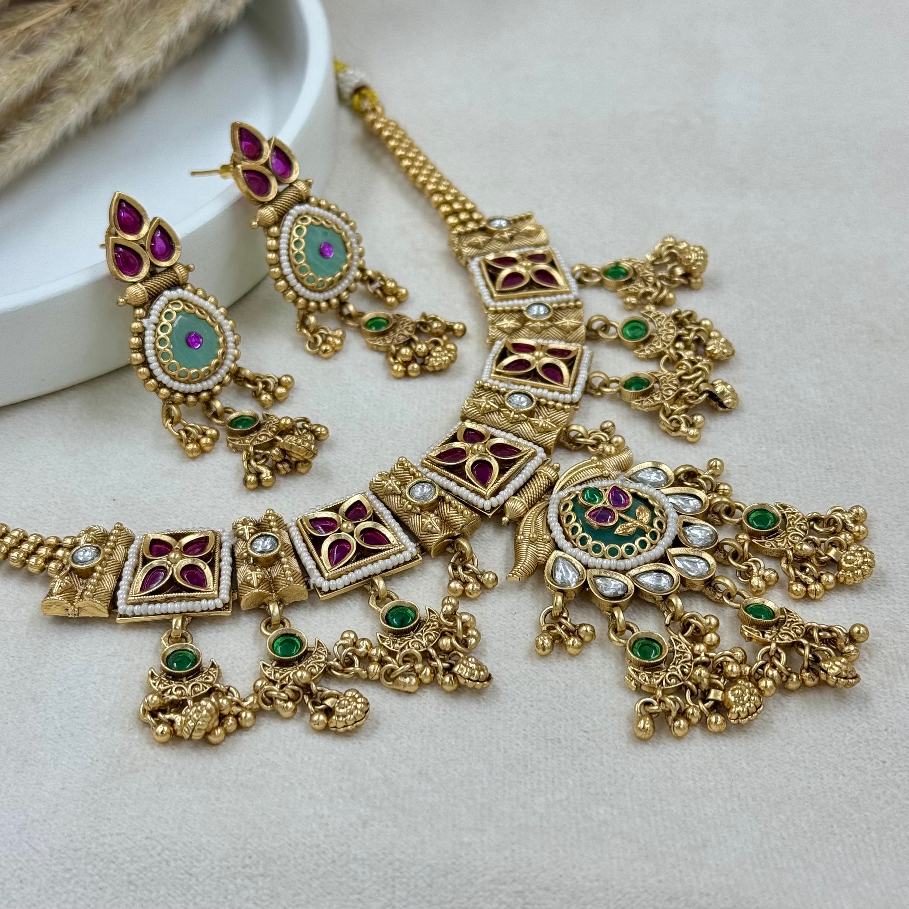 Ornate gold necklace with gemstones on a light background