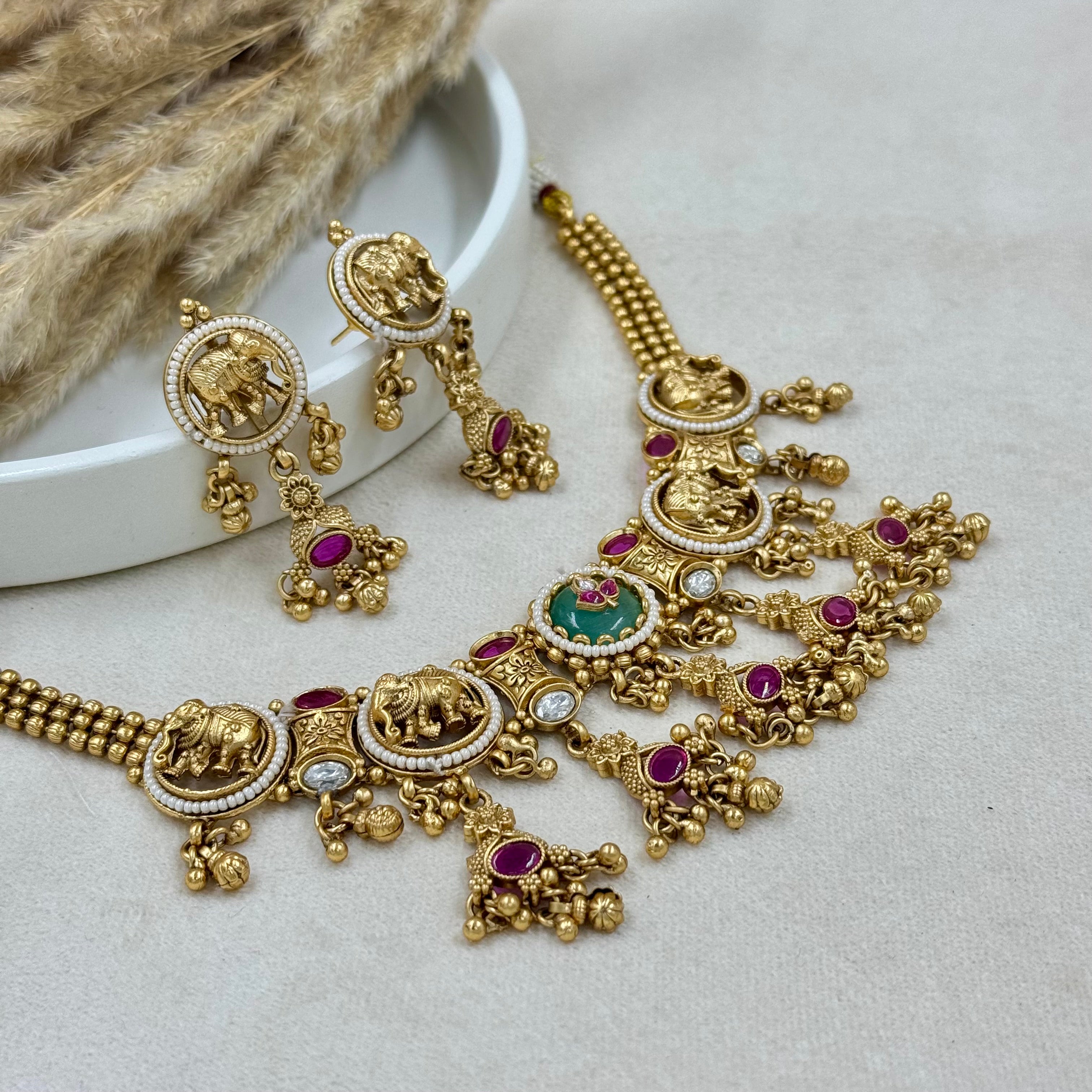 Ornate gold necklace with gemstones on a light background