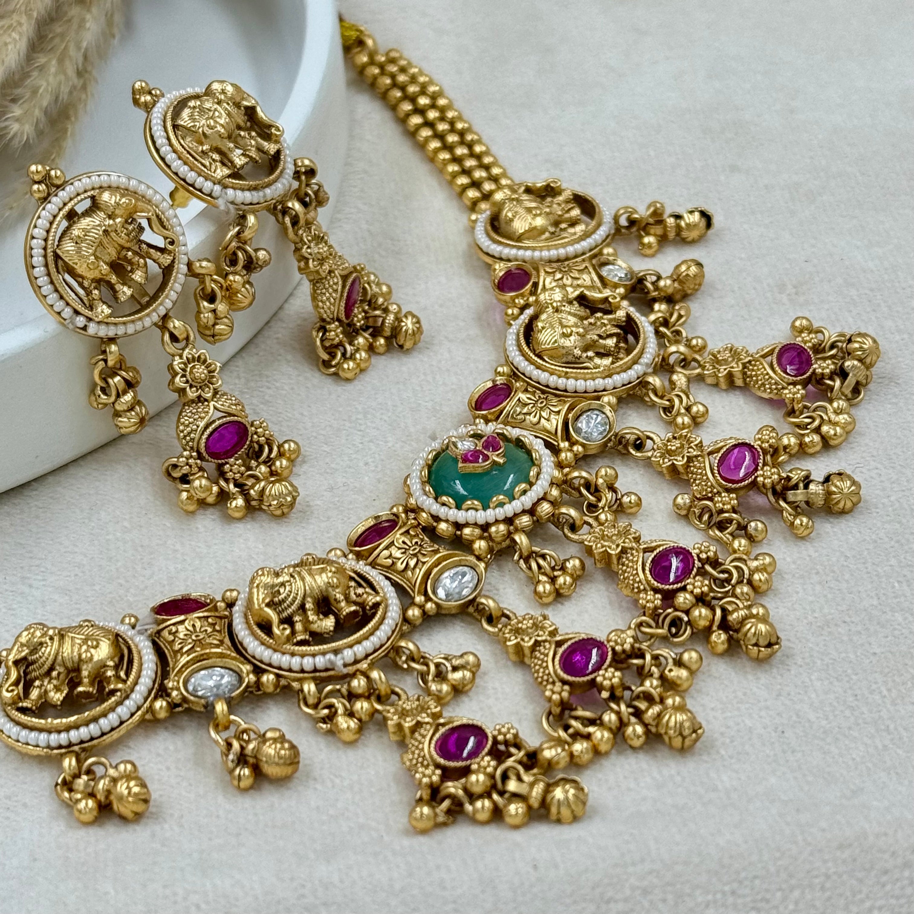 Ornate gold necklace with gemstones on a light background