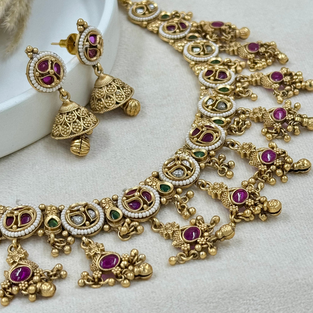 Gold necklace and earrings with gemstones on a white surface