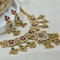Ornate gold jewelry set with gemstones on a light background