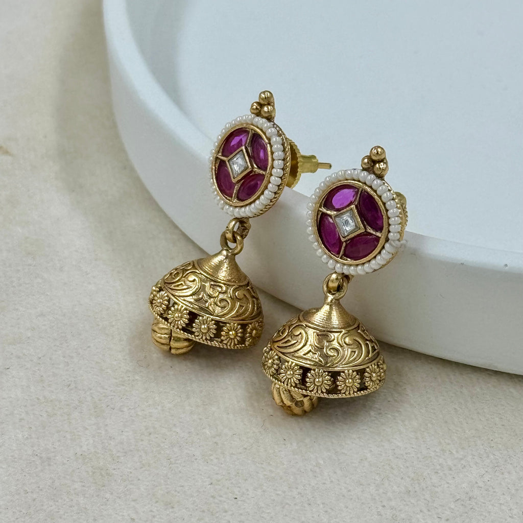Gold earrings with purple gemstones on a white background