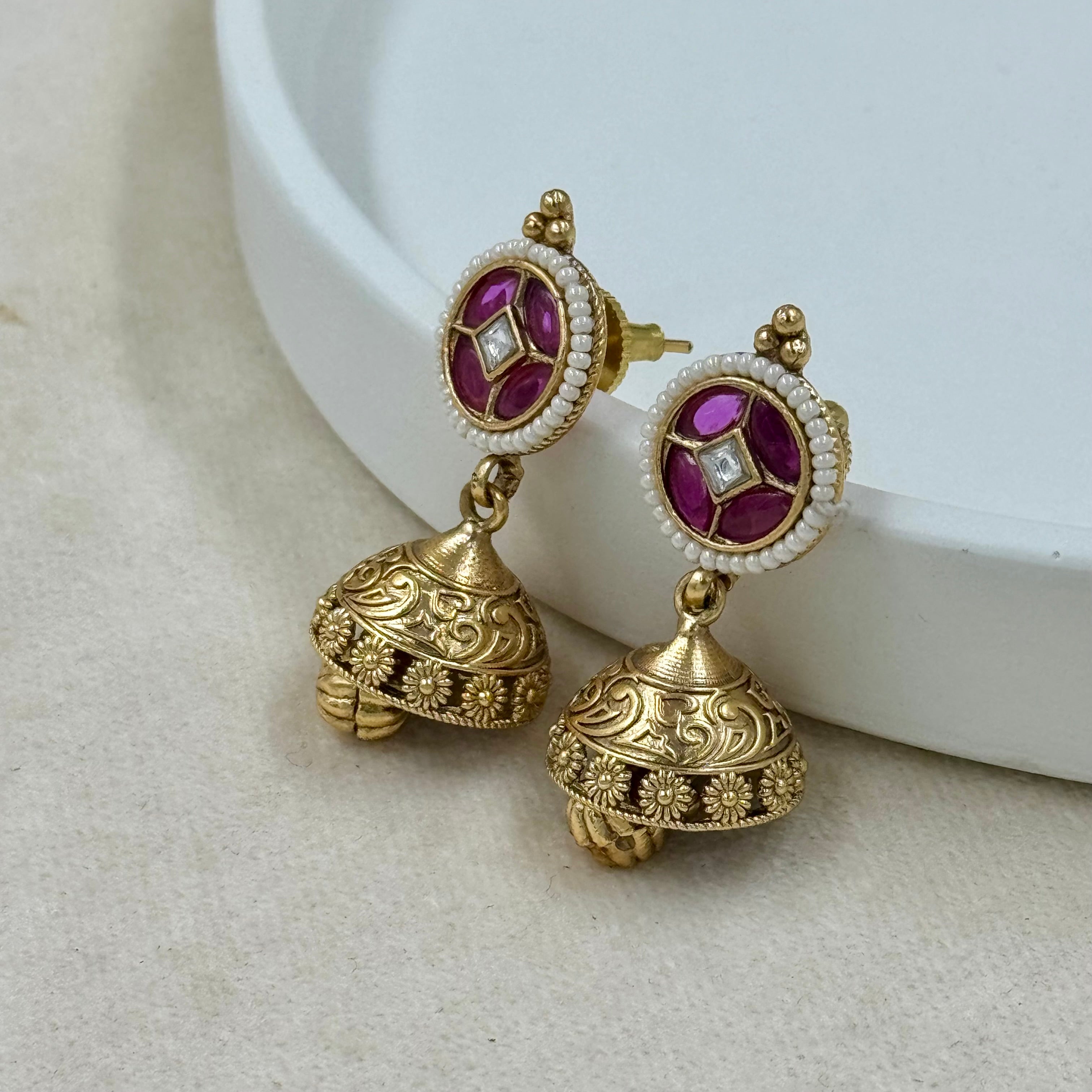 Gold earrings with purple gemstones on a white background