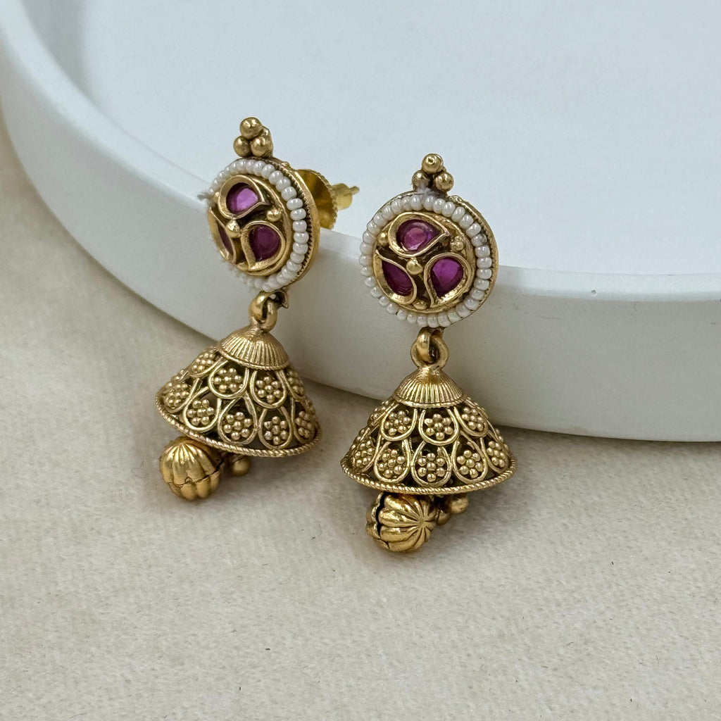 Gold earrings with purple gemstones on a white background