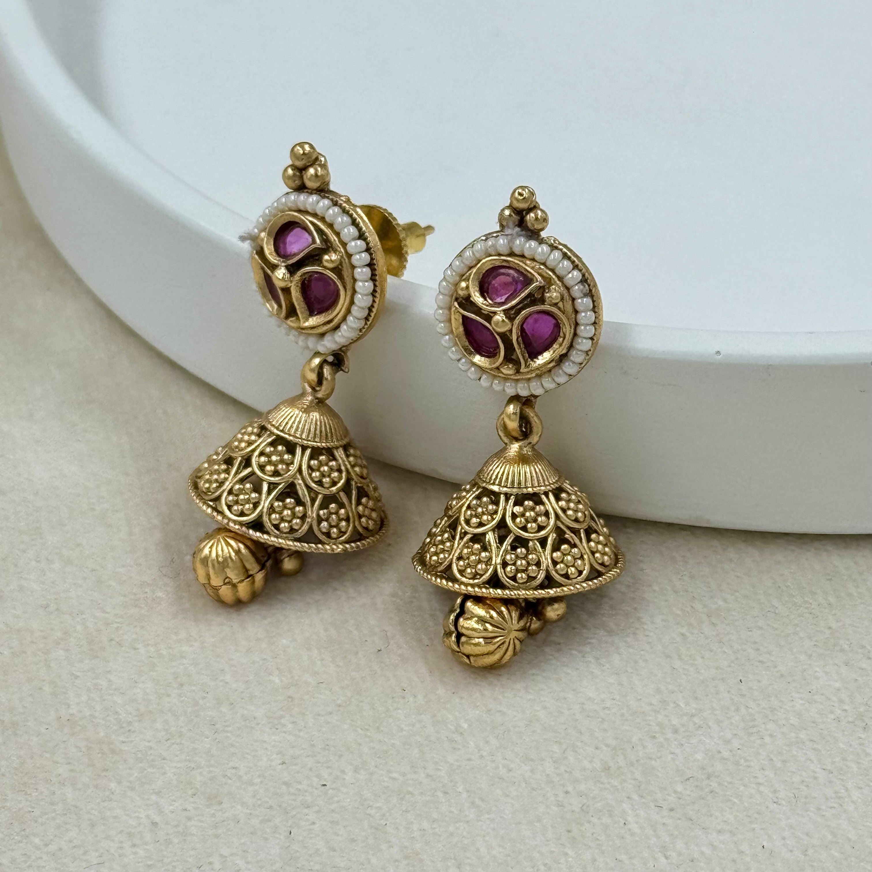 Gold earrings with purple gemstones on a white background