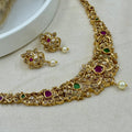 Gold necklace and earrings with gemstones on a light background