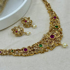 Gold necklace and earrings with gemstones on a light background