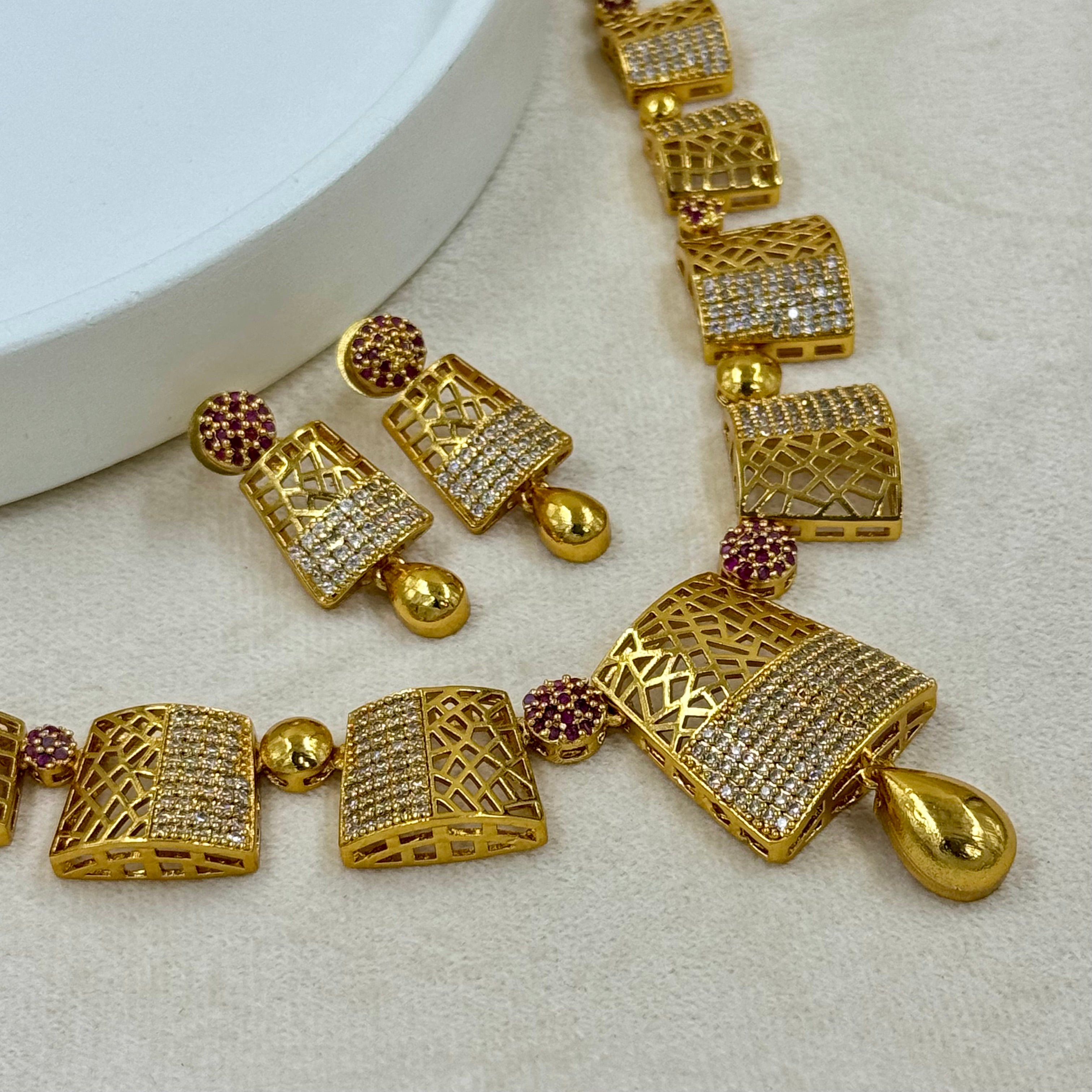 Gold necklace with intricate designs on a light gray background