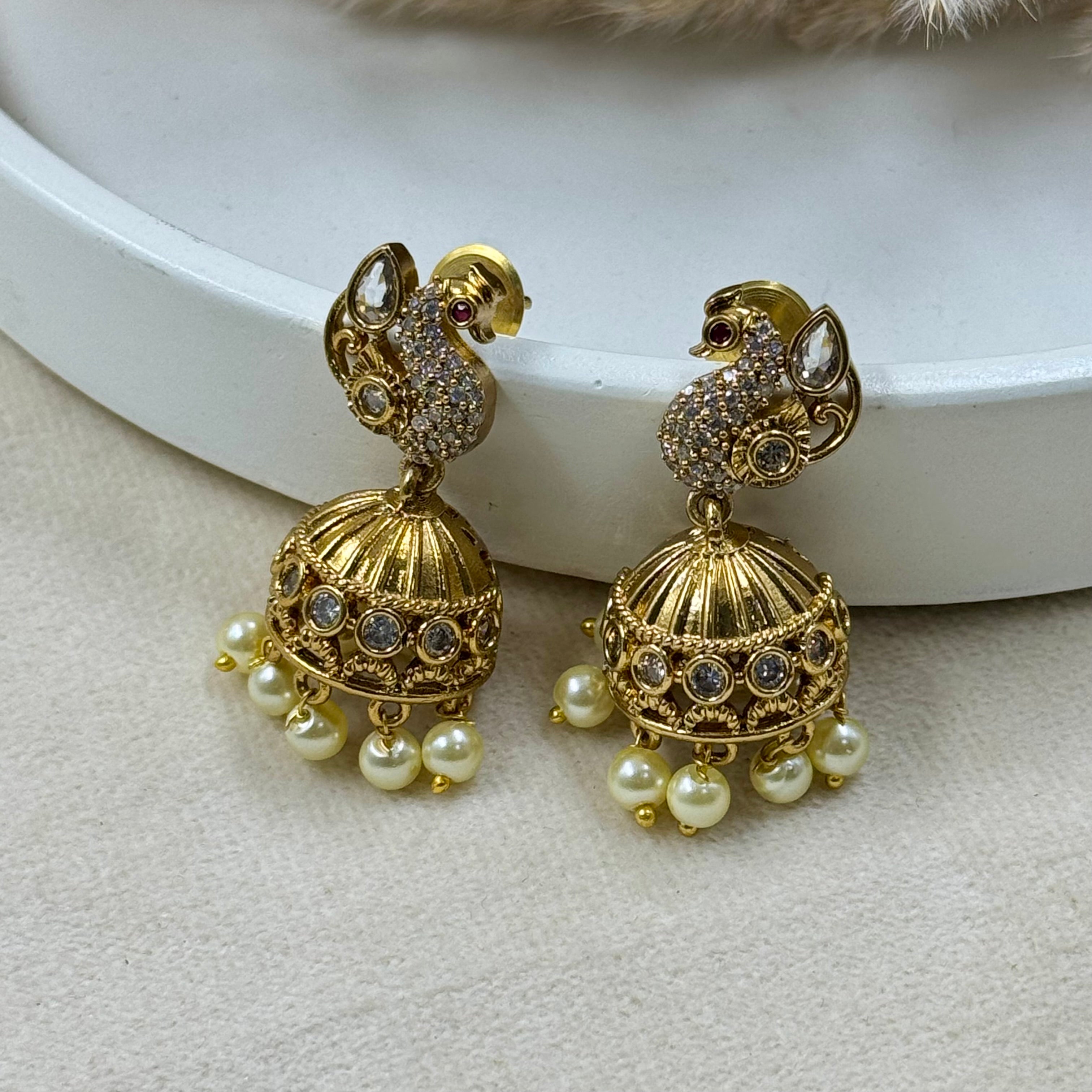 Gold earrings with pearl drops on a white surface