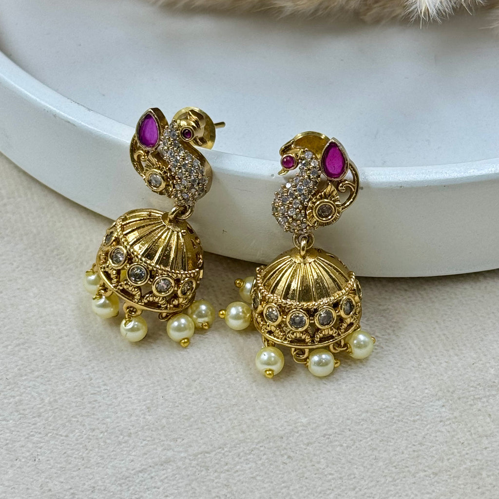 Gold earrings with pearls and gemstones on a light background