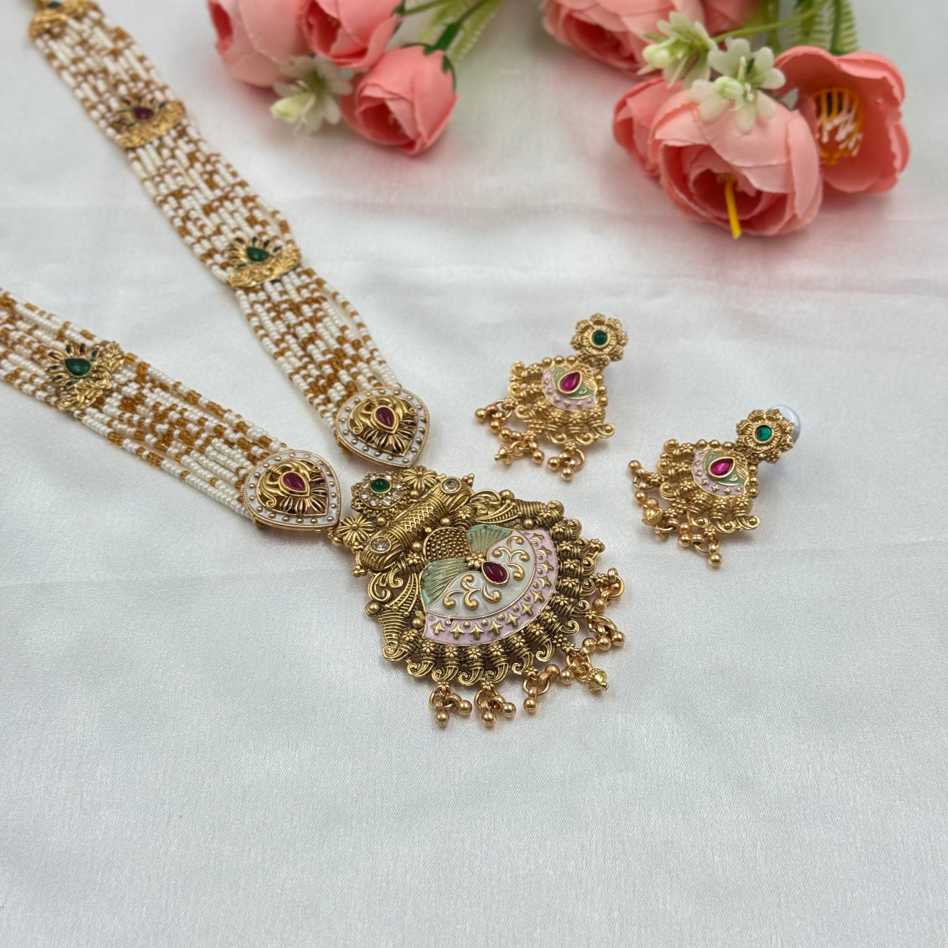 Gold necklace and earrings with pink flowers on a white background