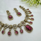 Jewelry set with necklace and earrings featuring red gemstones on a white background.
